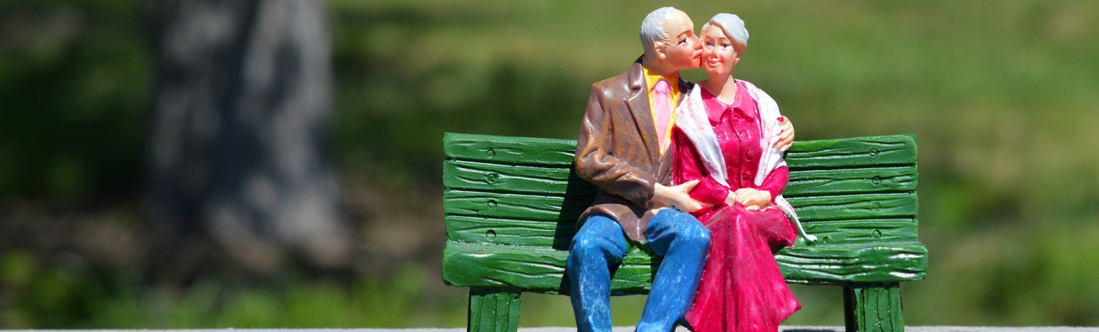 Zwei ältere Modellfigurern sitzen auf einer Parkbank