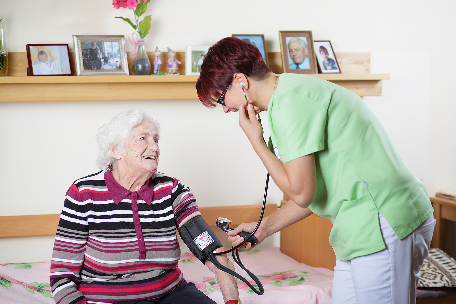 Eine Pflegemitarbeiterin misst den Blutdruck bei einer Bewohnerin