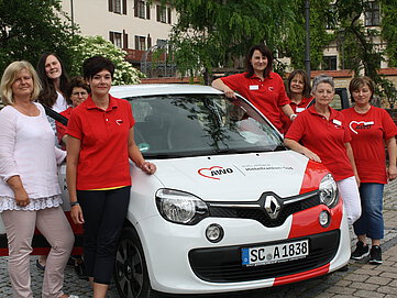 Das Team des Ambulanten Pflegediensten Altmühlfranken steht neben einem Auto