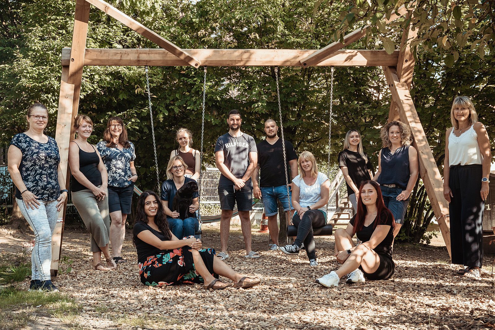 Das Kita-Team, bestehend aus 13 Personen, sitzt und steht rund um ein Klettergerüst.