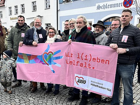 Eine Gruppe von AWO-Mitarbeitenden hält ein rosafarbenes Banner, auf dem "Wir l(i)eben Vielfalt" steht.